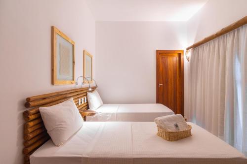 a white bedroom with two beds and a window at CasaLô Hotel in Jericoacoara