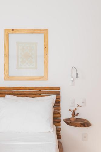 a bedroom with a white bed with a wooden headboard at CasaLô Hotel in Jericoacoara