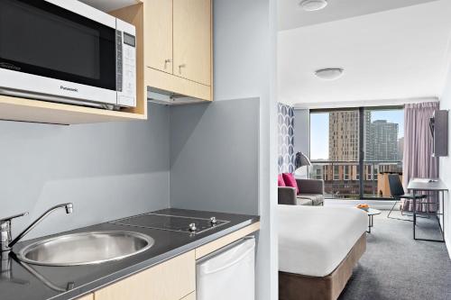 eine Küche mit einer Spüle und einer Mikrowelle in der Unterkunft Mantra Sydney Central in Sydney