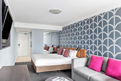 a living room with a bed and a couch at Mantra Sydney Central in Sydney