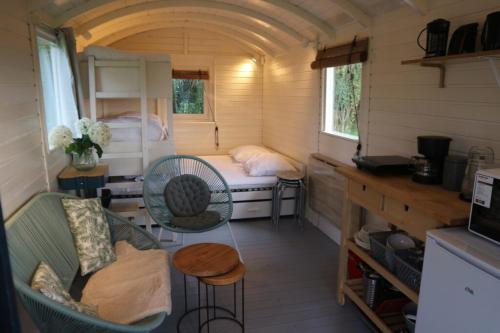 um pequeno quarto com uma cama, uma mesa e cadeiras em Pipowagen Jasmijn bij Pipowagen en kampeerhoeve s Gravenhof em Netterden