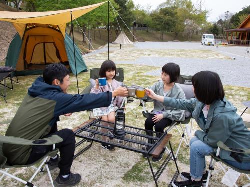 a group of people sitting around a table in front of a tent at Matsue Forest Park in Matsue