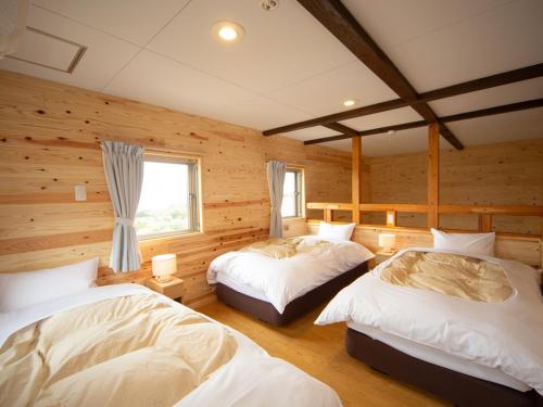 two beds in a room with wooden walls at Matsue Forest Park in Matsue