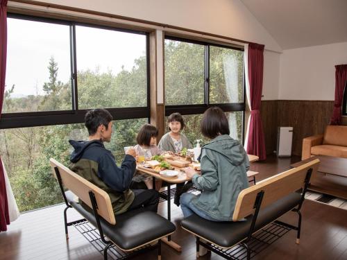 a family eating dinner at a table in a room with large windows at Matsue Forest Park in Matsue