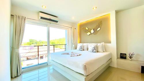 The Palms Residence - SHA Extra Plus في فوكيت تاون: غرفة نوم بسرير ونافذة كبيرة