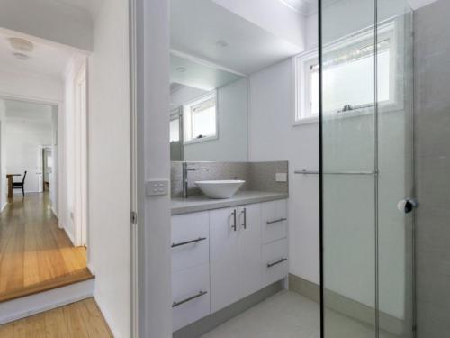 a white bathroom with a sink and a glass shower at Woodlands Retreat Rye in Rye
