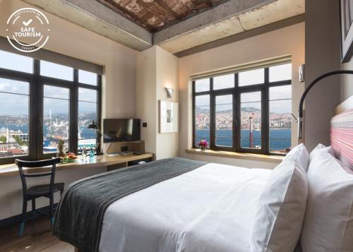 a bedroom with a bed and a desk and windows at Bankerhan Hotel Galata - Adults Only Special Category in Istanbul