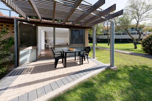 a patio with a table and chairs under a pergola at Shefayim Kibbutz Hotel in Kibbutz Shefayim
