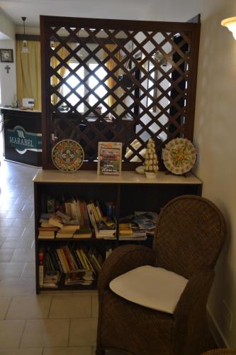 a table and two chairs and a book shelf with books at Hotel Marabel in SantʼAlessio Siculo