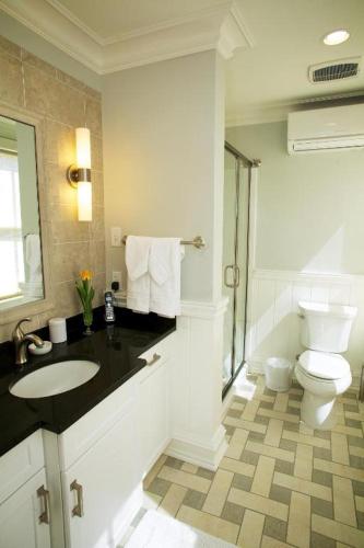 a white bathroom with a toilet and a sink at Norwalk Inn & Conference Center in Norwalk