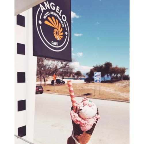 a person holding an ice cream cone in front of a sign at ANGELO Cafe Hotel in Tolo