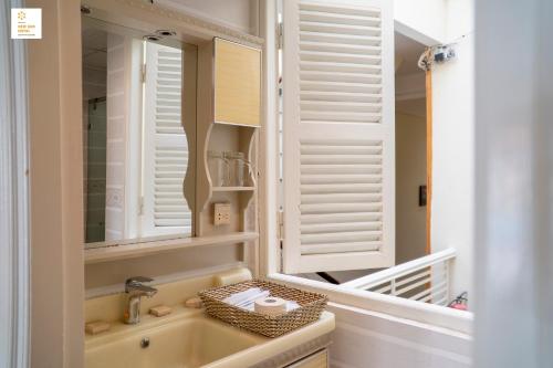 une salle de bain avec des fenêtres à volets blancs et un lavabo dans l'établissement New Sun Hotel Đà Lạt, à Đà Lạt