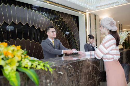 a man and woman standing at a counter in a lobby at Muong Thanh Sapa Hotel in Sa Pa