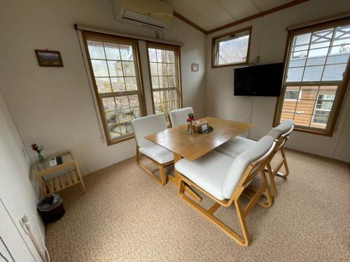 a dining room with a wooden table and chairs at Hakuba Canadian Lodge in Hakuba