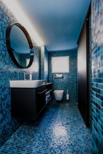 a blue bathroom with a sink and a mirror at HEINRICH Stadtwohnung im Jüdischen Viertel in Hohenems