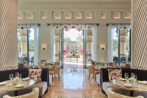 a restaurant with tables and chairs and a large window at Jumeirah Al Qasr Dubai in Dubai