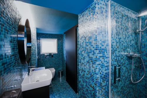 a blue bathroom with a sink and a shower at HEINRICH Stadtwohnung im Jüdischen Viertel in Hohenems