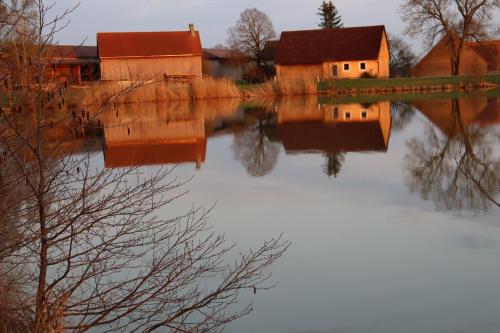 un reflejo de una casa en un cuerpo de agua en Zur Altmühlquelle, en Windelsbach