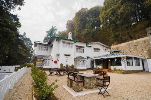ナイニタールにあるBhikampur Lodge By Nine Hotelsの白い大きな建物(椅子、テーブル付)