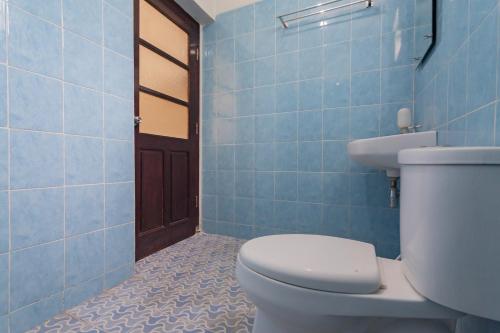 a blue tiled bathroom with a toilet and a sink at RedDoorz Syariah @ Kolonial Guest House in Majalengka