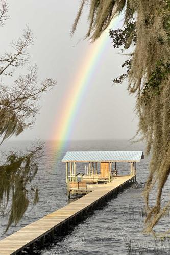 a rainbow over a dock in the water with a dock at Renovated Crescent Lake Escape with Waterfront Deck! in Crescent City