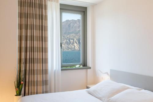 a bedroom with a window with a view of the ocean at Hotel Lago Di Garda in Nago-Torbole