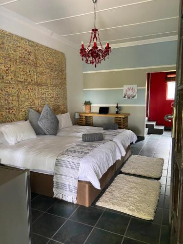 a bedroom with a large bed with a chandelier at Karoozin Village in Oudtshoorn