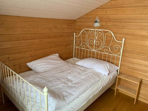 a white bed in a room with wooden walls at Berghaus Niederhorn in Beatenberg