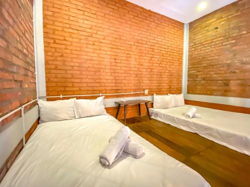 a room with two beds and a brick wall at Griya Gribig Guest House Mitra RedDoorz in Malang