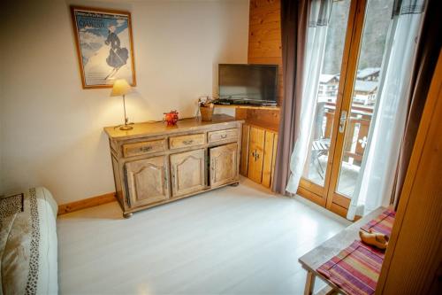 Habitación con armario de madera, TV y ventana. en L Aravis (Gite des Alpes), en La Giettaz