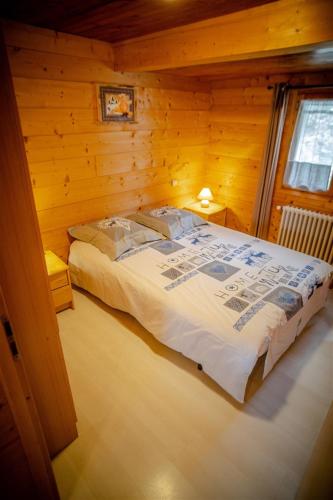 une chambre avec un lit dans une cabane en rondins dans l'établissement L Aravis (Gite des Alpes), à La Giettaz
