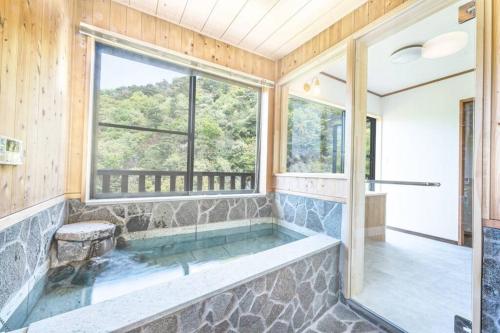 a large bathroom with a tub with a window at 南熱海あじろハウス in Atami