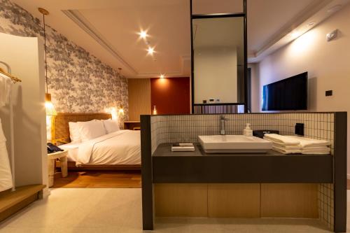 a bathroom with a sink and a bed and a mirror at Hound Garden&Terrace Hotel in Busan