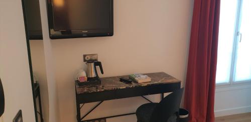 a table with a coffee maker and a television on a wall at Acacias Etoile in Paris