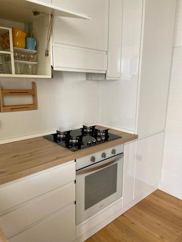 a white kitchen with a stove and white cabinets at Ada's House in Alghero