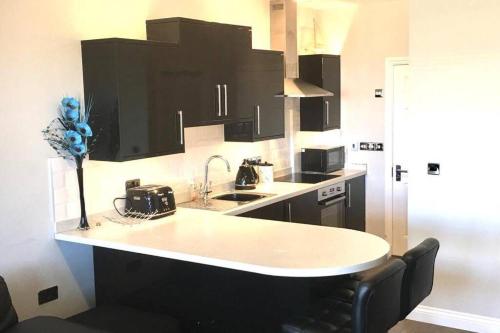 a kitchen with a white counter and black cabinets at Entire Ground Floor Apartment - West Bay in West Bay