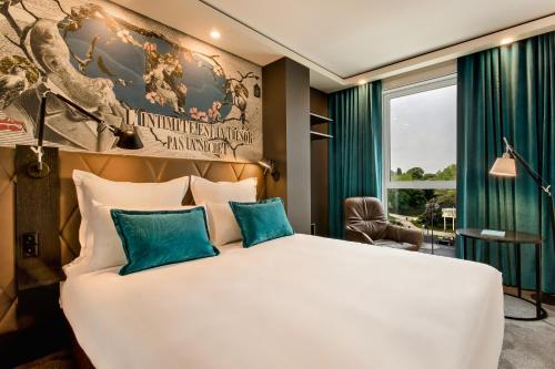 1 dormitorio con 1 cama blanca grande con almohadas azules en Motel One Paris-Porte Dorée, en París