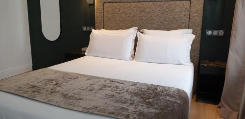 a bedroom with a bed with white sheets and pillows at Acacias Etoile in Paris