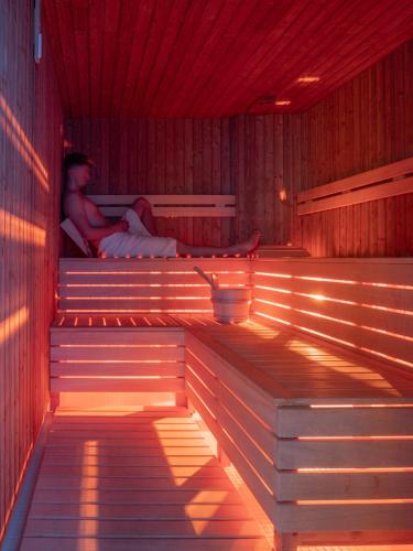 a person sitting on a bench in a sauna at Tee House Čeladná in Čeladná