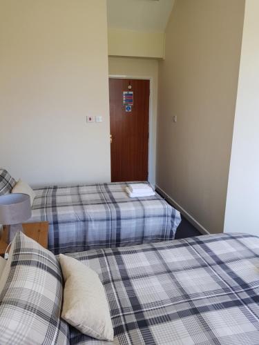 two beds in a small room with a door at The Chase Inn in Bishops Frome