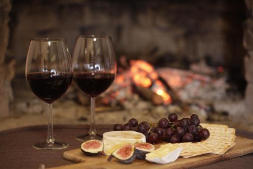 two glasses of wine next to cheese and grapes in front of a fireplace at Forest Hills in Knysna