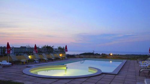 a swimming pool at night with chairs and tables at Abbaidda Hotel in Valledoria