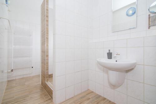 a white bathroom with a sink and a shower at Penzion Anareta in Frýdek-Místek