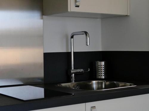 a stainless steel sink in a black and white kitchen at Appart'hôtel Chambrappart in Falaise