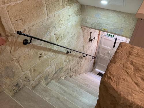 a staircase with a stone wall and a white door at Charming house in the heart of Valletta CPAC1-3 in Valletta