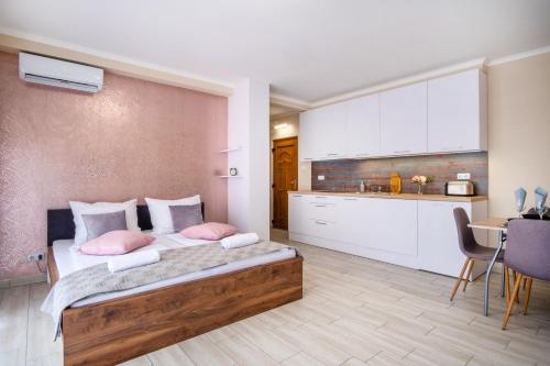 a bedroom with a bed with pink pillows and a kitchen at MyFlat Siófok Beach Wellness Apartment in Siófok