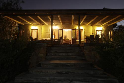 a house with lights on the porch at night at Forest Hills in Knysna