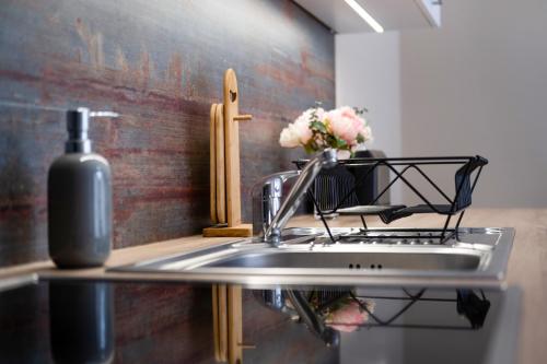 a kitchen sink with a bottle of soap and flowers at MyFlat Siófok Beach Wellness Apartment in Siófok