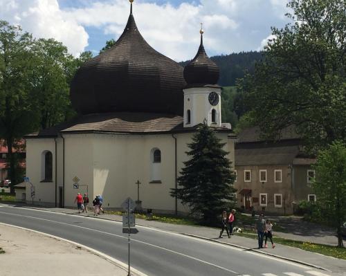 a building with a clock tower on the side of a road at Apartmany Rezidence Klostermann & Javor & Skalka in Železná Ruda