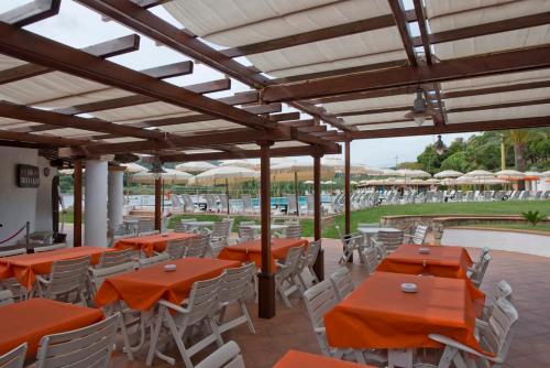 - patio z pomarańczowymi stołami i białymi krzesłami w obiekcie Hotel Cala di Mola w mieście Porto Azzurro